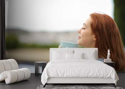 Woman smelling coffee in a terrace at hotel Wall mural