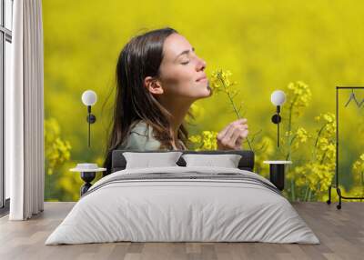 Woman smelling flowers in a yellow field Wall mural