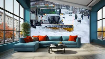 Front view of city services snow plow truck with yellow blade cleaning roads after winter storm with kids playing in the background Wall mural