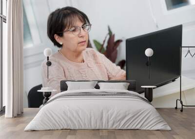 beautiful middle age woman using laptop in home Wall mural