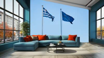 Greek and European Flag waving on two parallel flagpoles next to each other in front of a clear light blue sky. 
International spirit and national symbols.  Wall mural