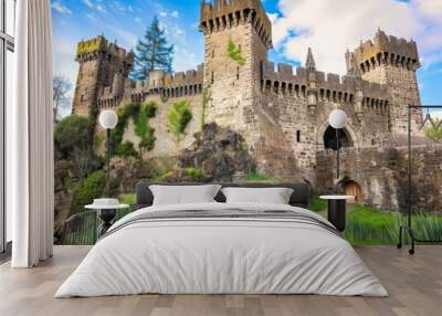 A historic castle with towering stone walls, intricate details, a grand entrance, lush green surroundings, and a moat.  Wall mural