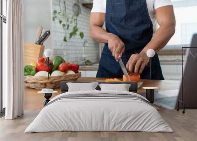 Asian strong man Wearing an apron having fun while preparing ingredients such as fruits and vegetables. learn how to do Chopping Carrots via Application Happily online in the kitchen. Wall mural