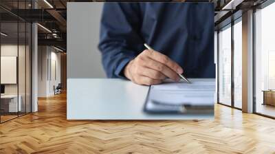 Young businessman, real estate insurance salesman reading and reviewing information Details of the agreement before signing the contract approval at home office investment and mortgage. Wall mural