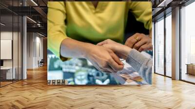 Thai female jewelry seller put gold bracelet on a customer hand for trying or fitting. Wall mural