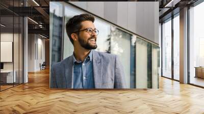 Closeup portrait Handsome young man in front of modern office smiling and looking in the distance  Wall mural