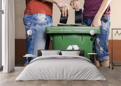 two unrecognizable man throwing smartphones in recycle bin , outdated, obsolete technology Wall mural