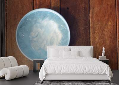 Silver water bowl with water and ice on wooden background. Wall mural