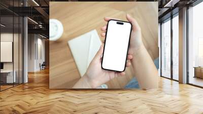 Young woman holding smartphone with empty screen over wooden table Wall mural