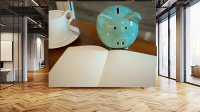 Blue piggy bank on the table with laptop and a cup of coffee. Wall mural