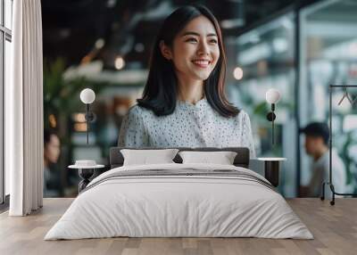 A successful Asian businesswoman standing in her startup's office, surrounded by creative team members, holding a tablet and smiling as she oversees the development of a new product Wall mural