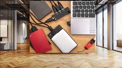 External hard drives connected to a laptop on wooden desk, top view Wall mural