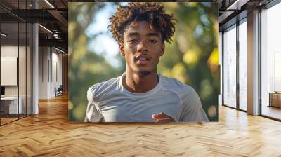 A Black teenager with curly hair, wearing white running shorts and a T-shirt, runs in the park on an early morning.  Wall mural