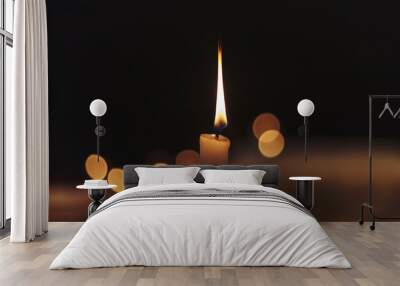 One light candle burning brightly in the black background Wall mural