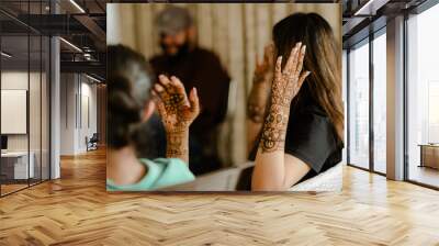 Artist applying henna tattoo on women hands. Mehndi is traditional Indian decorative art. Wall mural