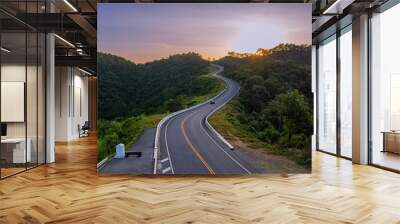 A mountain road with many curves winding through lush and lush forests and beautiful natural views on both sides during the morning sunrise in Nan Province, Thailand, Asia. Wall mural