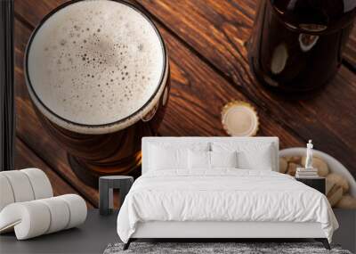 glass of dark cold frothy beer, nuts, bottle, cap, old wooden ta Wall mural