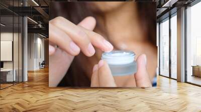 Hand of woman holding moisturizer cream and serum. She applying a facial cream , essential , oil , lotion and body cream for skin care. Beauty and Healthy Concept. Wall mural