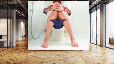 Woman sitting on the toilet bowl in the bathroom. She has stomach ache. Poor digestive system. Constipation. Diarrhea. Food poisoning. Health and medicine.	
 Wall mural