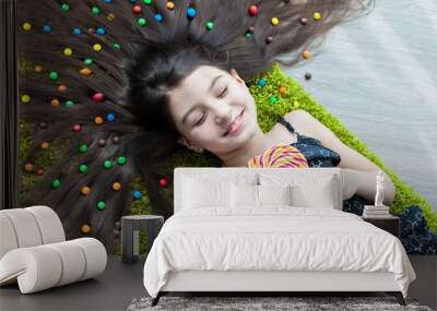 Little girl lying on the floor with his eyes closed and eating candy Wall mural