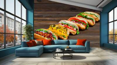 lot of big delicious hot dogs with sauce and vegetables on wooden background. Wall mural