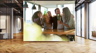 Smiling colleagues toasting drink bottles in office Wall mural