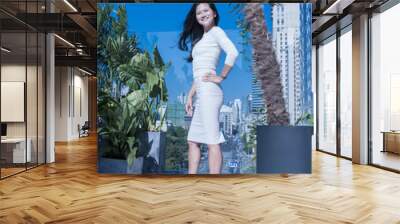 A beautiful young woman is standing on office buildings background Wall mural