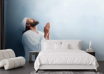 A serene depiction of a man in prayer, looking upward with hands clasped, symbolizing faith, devotion, and spiritual connection. Wall mural