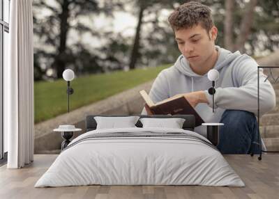 Christian worship and praise. A young man is praying and reading the bible in the evening. Wall mural