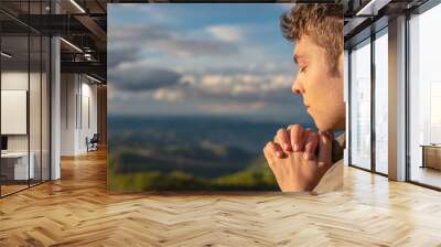 Christian worship and praise. A young man is praying and worshiping in the evening. Wall mural