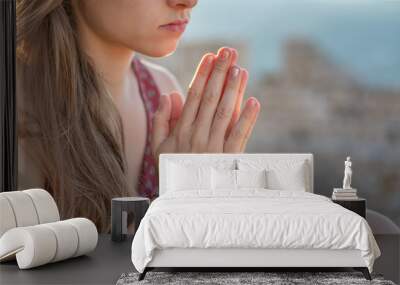 Christian worship and praise. A young woman is praying with ruins in the background. Wall mural