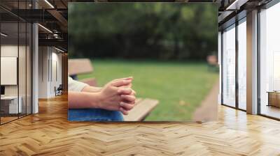 Christian worship and praise. A young woman is sitting and praying on a park bench. Wall mural