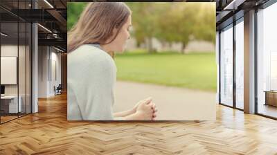 Christian worship and praise. A young woman is sitting and praying on a park bench. Wall mural