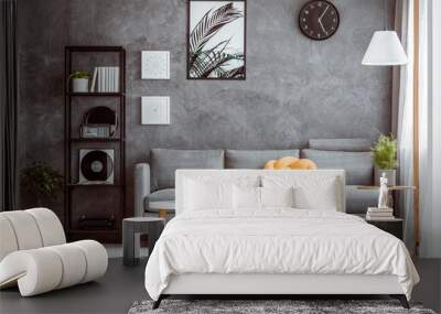 Black clock above grey settee Wall mural