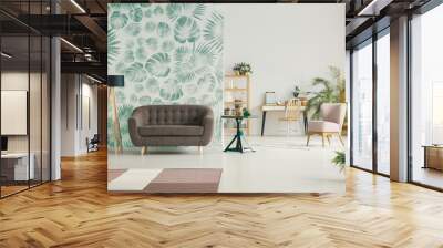 Brown sofa next to lamp in apartment interior with leaves wallpaper and pink chair. Real photo Wall mural