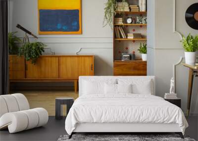 Chair at desk with gold lamp in grey apartment interior with plants on wooden cabinet. Real photo Wall mural