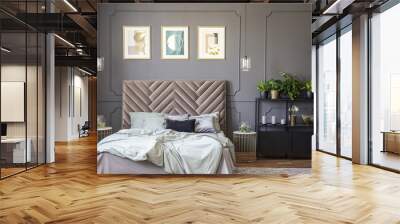 Dark grey bedroom interior with wainscoting on the wall, king-size bed with soft bedhead, three posters and metal rack with plants and decor Wall mural