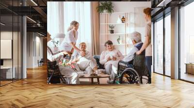 Disabled grandparents spending time in common room with their caregivers Wall mural