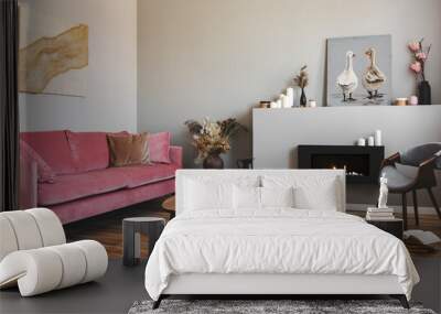 Dry flowers in pottery vase on small wooden table next to velvet pink couch in grey living room Wall mural