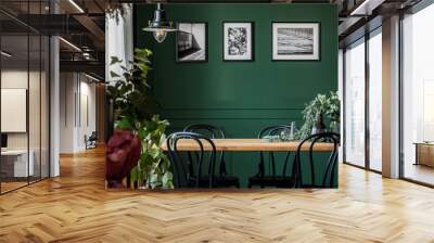 Green flowers in glass vase on long wooden table with black chairs in elegant living room Wall mural