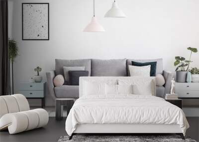 Grey sofa with pillows in white apartment interior with poster and plants on cabinets. Real photo Wall mural