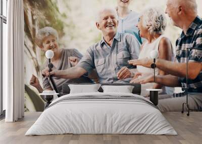 Happy elderly man with walking stick and smiling senior people relaxing in the garden Wall mural