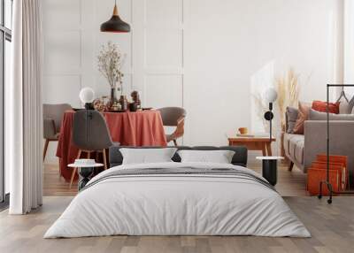 Living and dining room interior with grey couch and table covered with orange tablecloth Wall mural