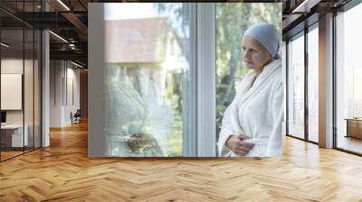 Lonely woman with cancer standing next to a window Wall mural