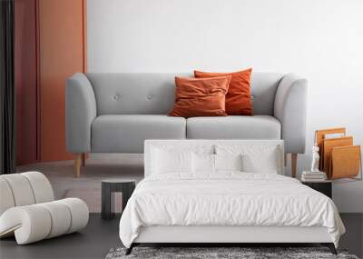 Orange pillows on grey sofa in grey living room interior with pink carpet and screen. Real photo Wall mural