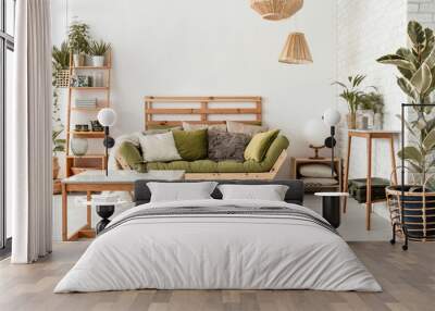 Pillows on green settee in natural botanic living room interior with wooden table and plants. Real photo Wall mural