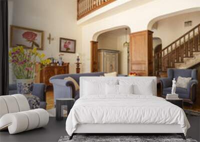 Real photo of a living room interior with blue sofa, rug, porcelain vase with flowers and stairs Wall mural