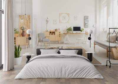 Real photo of a modern home office interior with wooden furniture, coffee table, sofa, pouf and computer on a desk Wall mural