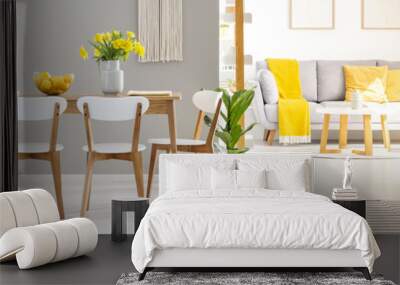 Real photo of a table with four chairs standing in living room interior with a couch, table, lamp and armchair in the background Wall mural