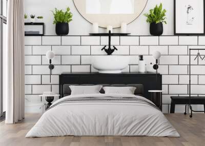 Real photo of black and white bathroom interior with fresh green plants, metal rack with towels and candles placed under mirror Wall mural